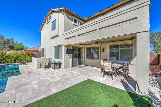 rear view of house featuring ceiling fan, a fenced in pool, and a patio