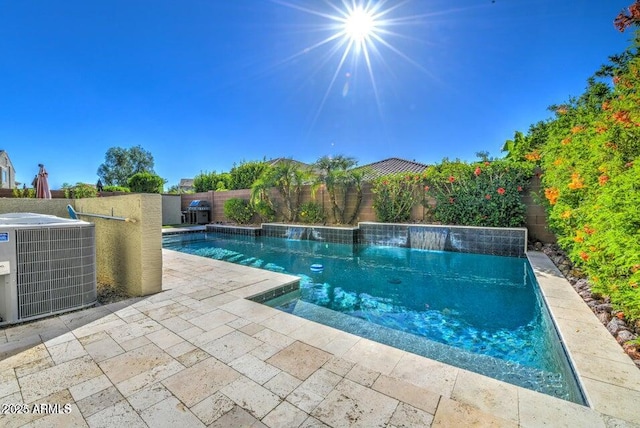 view of pool with pool water feature, a patio area, and central AC