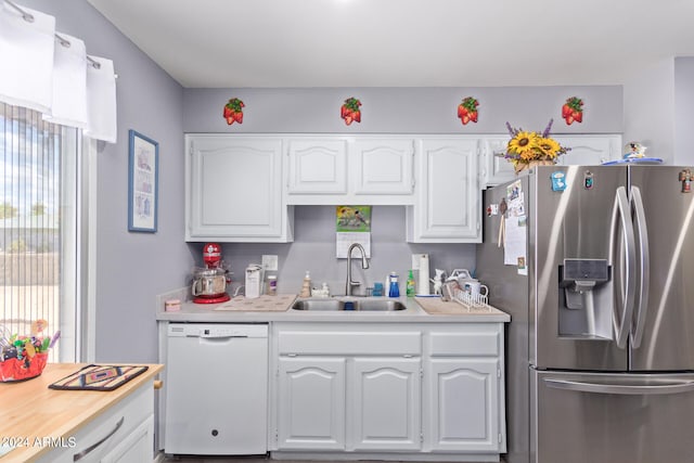 kitchen with stainless steel fridge, sink, white dishwasher, and white cabinets