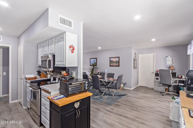 kitchen with light hardwood / wood-style flooring, white cabinets, appliances with stainless steel finishes, and butcher block countertops