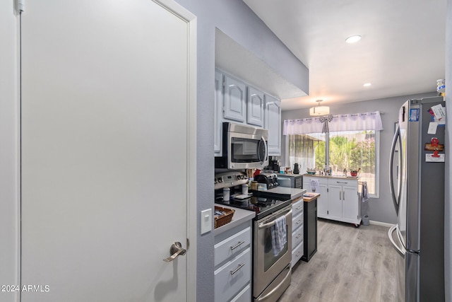 kitchen with appliances with stainless steel finishes and light hardwood / wood-style floors