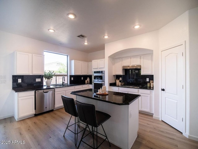 kitchen featuring stainless steel appliances, sink, white cabinets, a center island, and a breakfast bar area