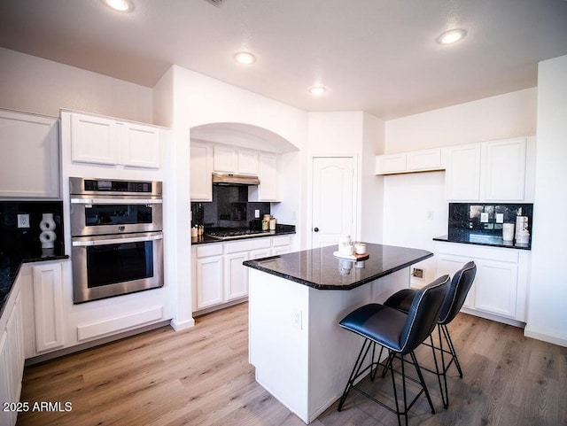 kitchen featuring white cabinets, appliances with stainless steel finishes, light hardwood / wood-style flooring, and a kitchen island