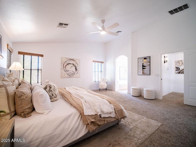 bedroom featuring ceiling fan, carpet floors, ensuite bathroom, and vaulted ceiling