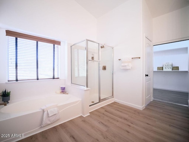 bathroom featuring hardwood / wood-style flooring, high vaulted ceiling, and shower with separate bathtub