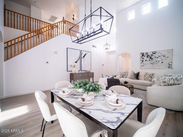 dining area featuring wood-type flooring and a high ceiling