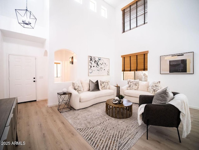 living room featuring a notable chandelier, a towering ceiling, and light hardwood / wood-style flooring