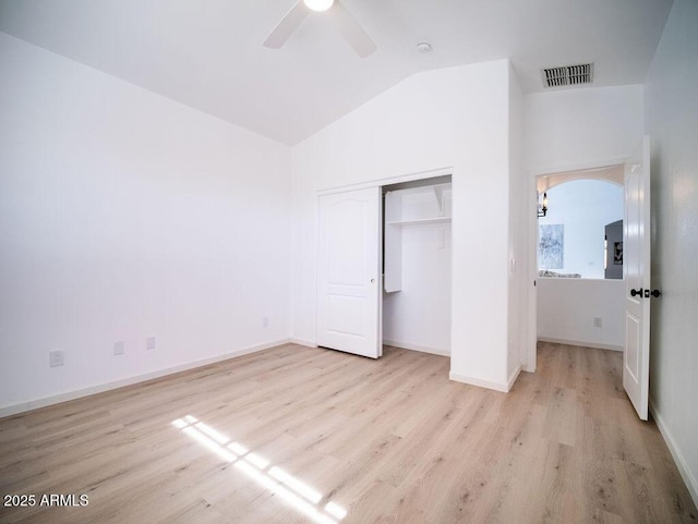 unfurnished bedroom with vaulted ceiling, a closet, light hardwood / wood-style flooring, and ceiling fan