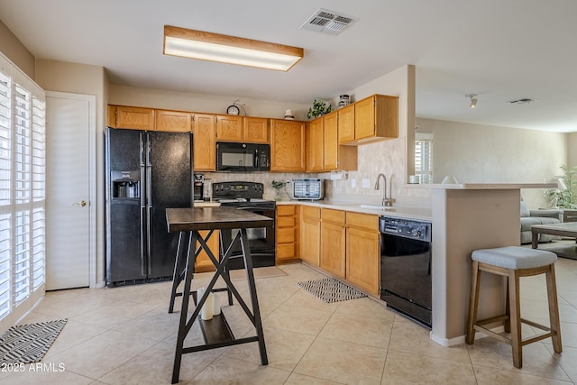 kitchen with sink, light tile patterned floors, black appliances, and plenty of natural light