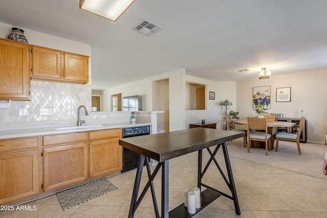 kitchen with decorative backsplash, black dishwasher, light tile patterned floors, and sink