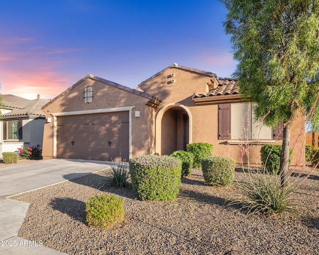 25969 W Tina Ln, Buckeye, AZ 85396 - mediterranean / spanish-style house featuring concrete driveway, stucco siding, an attached garage, and a tiled roof