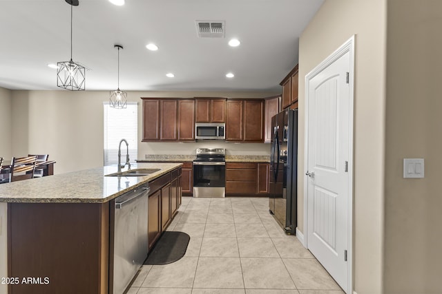 25969 W Tina Ln, Buckeye, AZ 85396 - kitchen with stainless steel appliances, recessed lighting, an island with sink, light tile patterned floors, and light stone counters