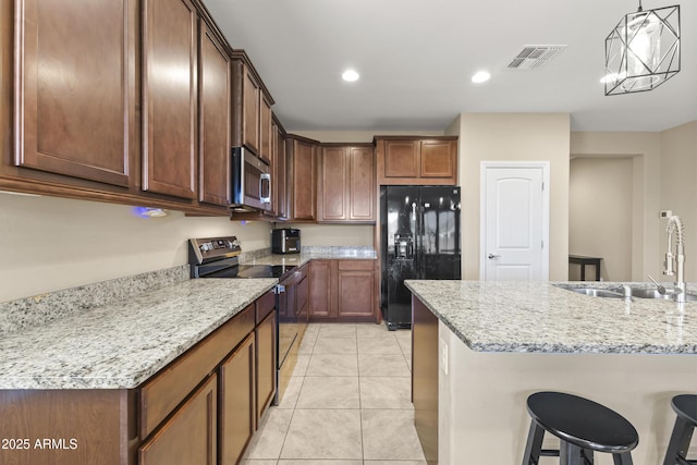 25969 W Tina Ln, Buckeye, AZ 85396 - kitchen with black appliances, a breakfast bar area, light tile patterned floors, light stone countertops, and recessed lighting