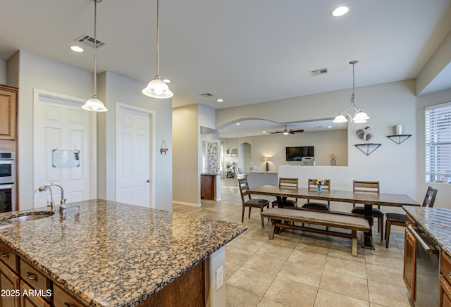 kitchen with arched walkways, open floor plan, visible vents, and a sink