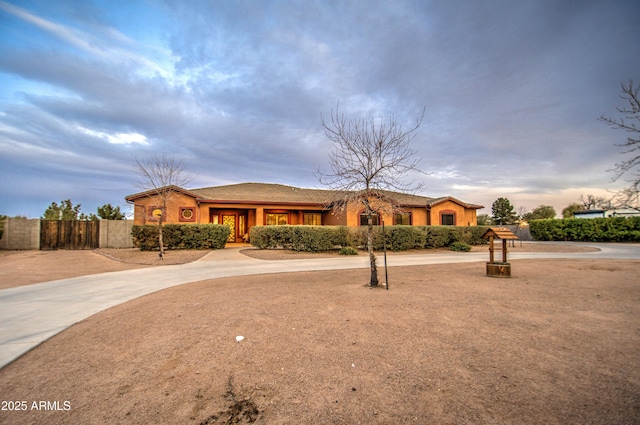 ranch-style house featuring fence and stucco siding