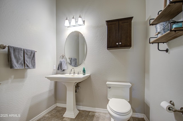 half bath with toilet, tile patterned flooring, and baseboards