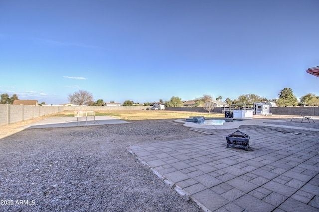 view of yard with a fire pit, a fenced in pool, a fenced backyard, an outdoor structure, and a patio area