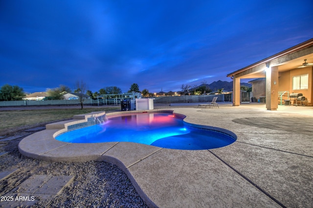 pool at dusk with a patio, a fenced backyard, and a fenced in pool