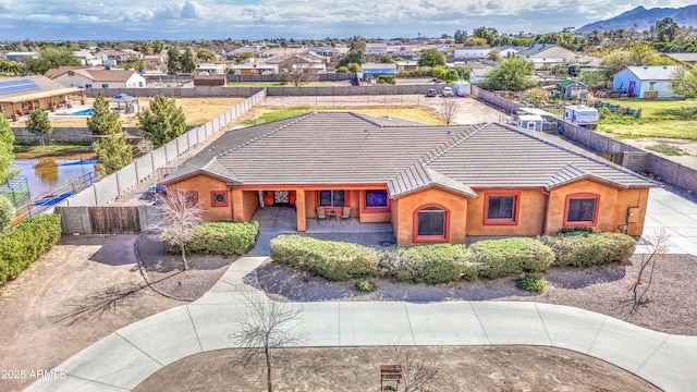 view of front facade featuring stucco siding, a gate, fence, a residential view, and a tiled roof