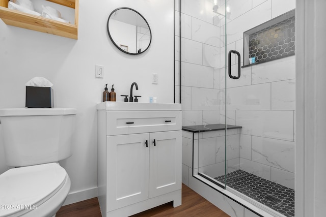 bathroom featuring hardwood / wood-style flooring, vanity, toilet, and a shower with door