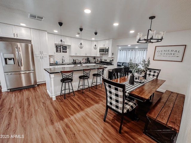 dining room with sink, a chandelier, and light wood-type flooring