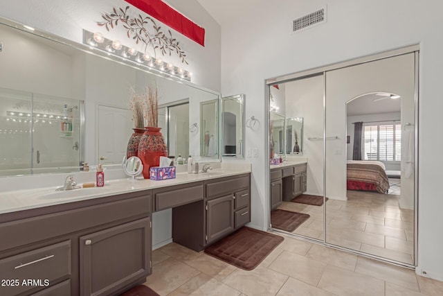 ensuite bathroom with visible vents, a sink, a shower stall, and double vanity