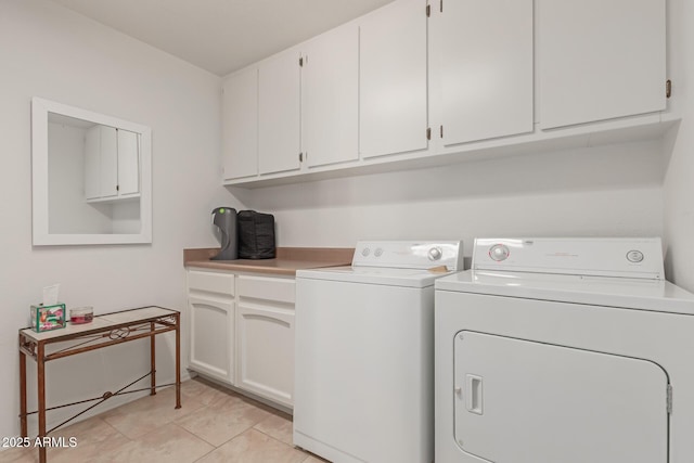 laundry area featuring light tile patterned floors, washer and clothes dryer, and cabinet space