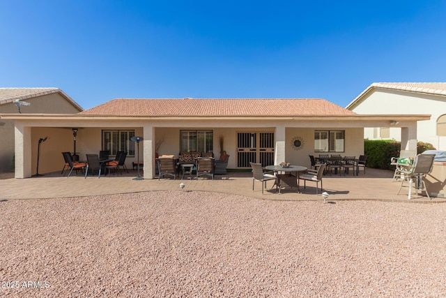 rear view of property with a tile roof, outdoor lounge area, a patio, and stucco siding