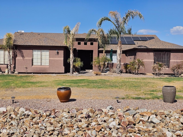 ranch-style home featuring solar panels and a front lawn