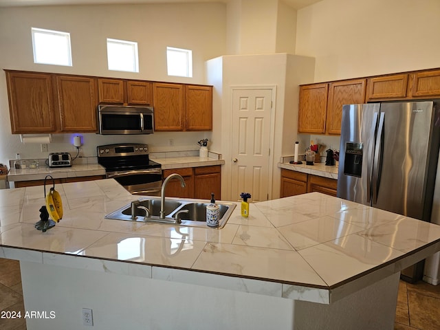 kitchen with stainless steel appliances, high vaulted ceiling, a kitchen island with sink, and sink