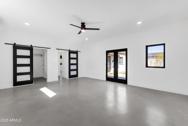 empty room featuring a barn door, baseboards, and concrete floors