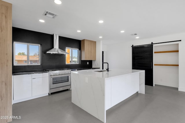 kitchen with high end range, modern cabinets, wall chimney exhaust hood, and a barn door