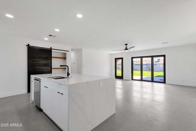 kitchen with visible vents, finished concrete flooring, dishwasher, a barn door, and a sink