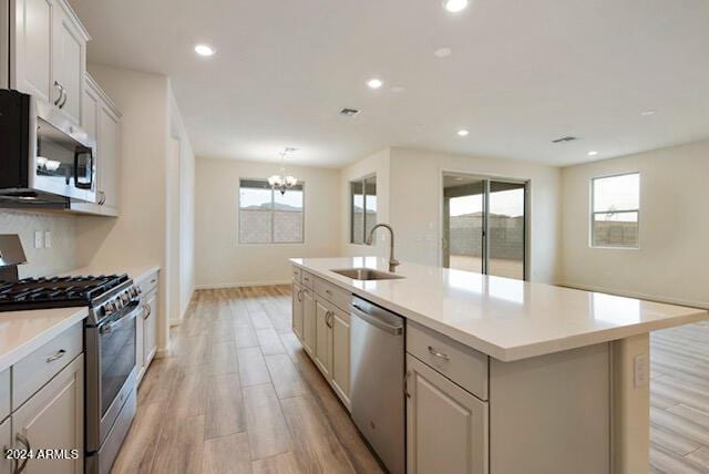 kitchen featuring appliances with stainless steel finishes, sink, plenty of natural light, and an island with sink