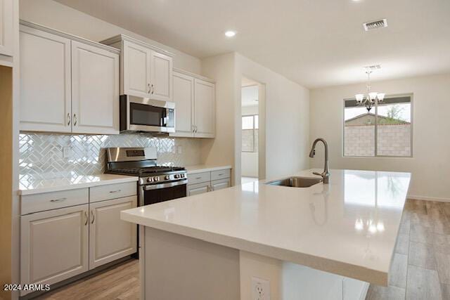 kitchen featuring a kitchen island with sink, sink, light hardwood / wood-style floors, and appliances with stainless steel finishes