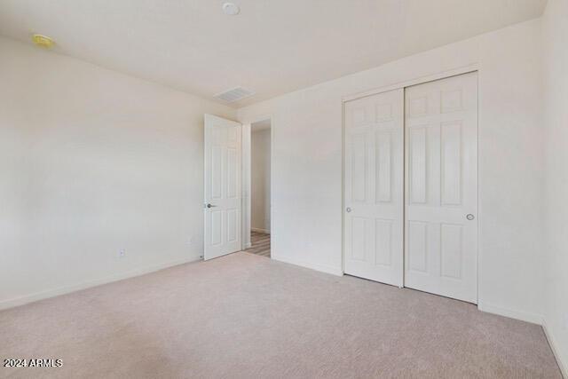 unfurnished bedroom with light carpet and a closet