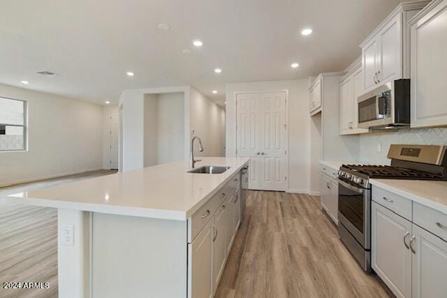 kitchen featuring white cabinetry, a kitchen island with sink, sink, and appliances with stainless steel finishes