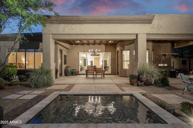 back house at dusk featuring a patio