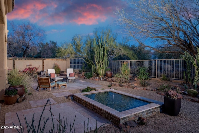 pool at dusk featuring a patio