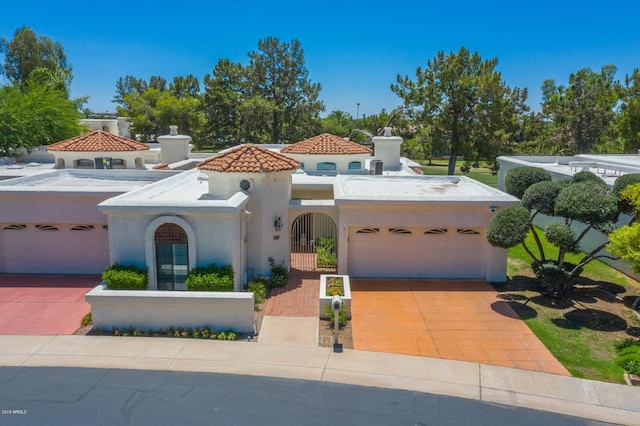 mediterranean / spanish house featuring a tiled roof, stucco siding, an attached garage, and driveway