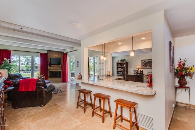 kitchen featuring light stone countertops, visible vents, a sink, a kitchen bar, and decorative light fixtures