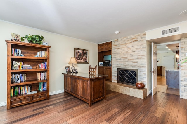 office with visible vents, ornamental molding, wood finished floors, a fireplace, and baseboards