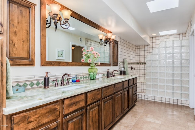 full bath with a sink, a chandelier, and double vanity