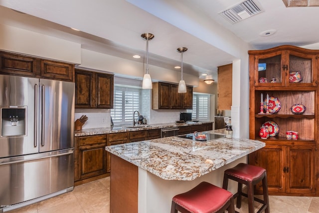 kitchen with visible vents, light stone countertops, stainless steel fridge with ice dispenser, black electric cooktop, and a sink