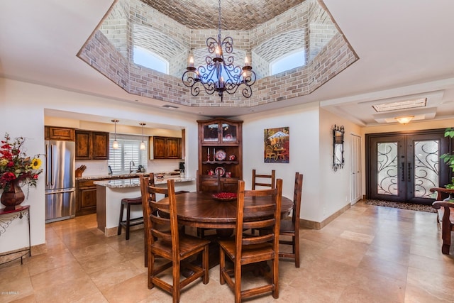 dining room featuring a notable chandelier, french doors, a high ceiling, brick ceiling, and baseboards