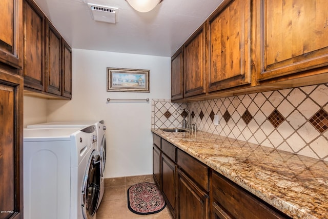 laundry area with visible vents, light tile patterned floors, washer and dryer, cabinet space, and a sink