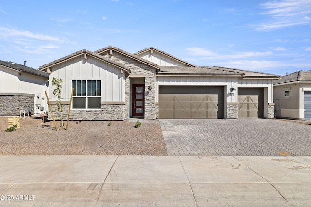 view of front facade featuring stone siding, decorative driveway, an attached garage, and board and batten siding