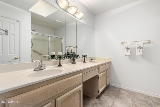 bathroom featuring double vanity, a skylight, a shower stall, and a sink