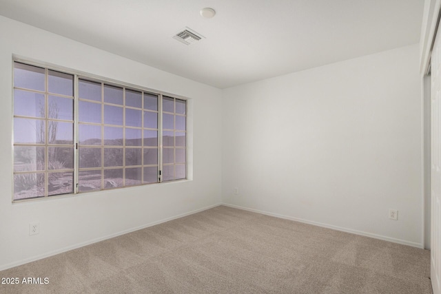 empty room featuring baseboards, visible vents, and carpet flooring