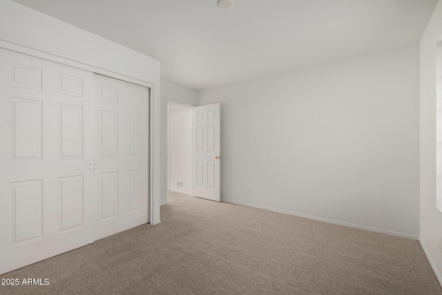 unfurnished bedroom with carpet floors, baseboards, and a closet